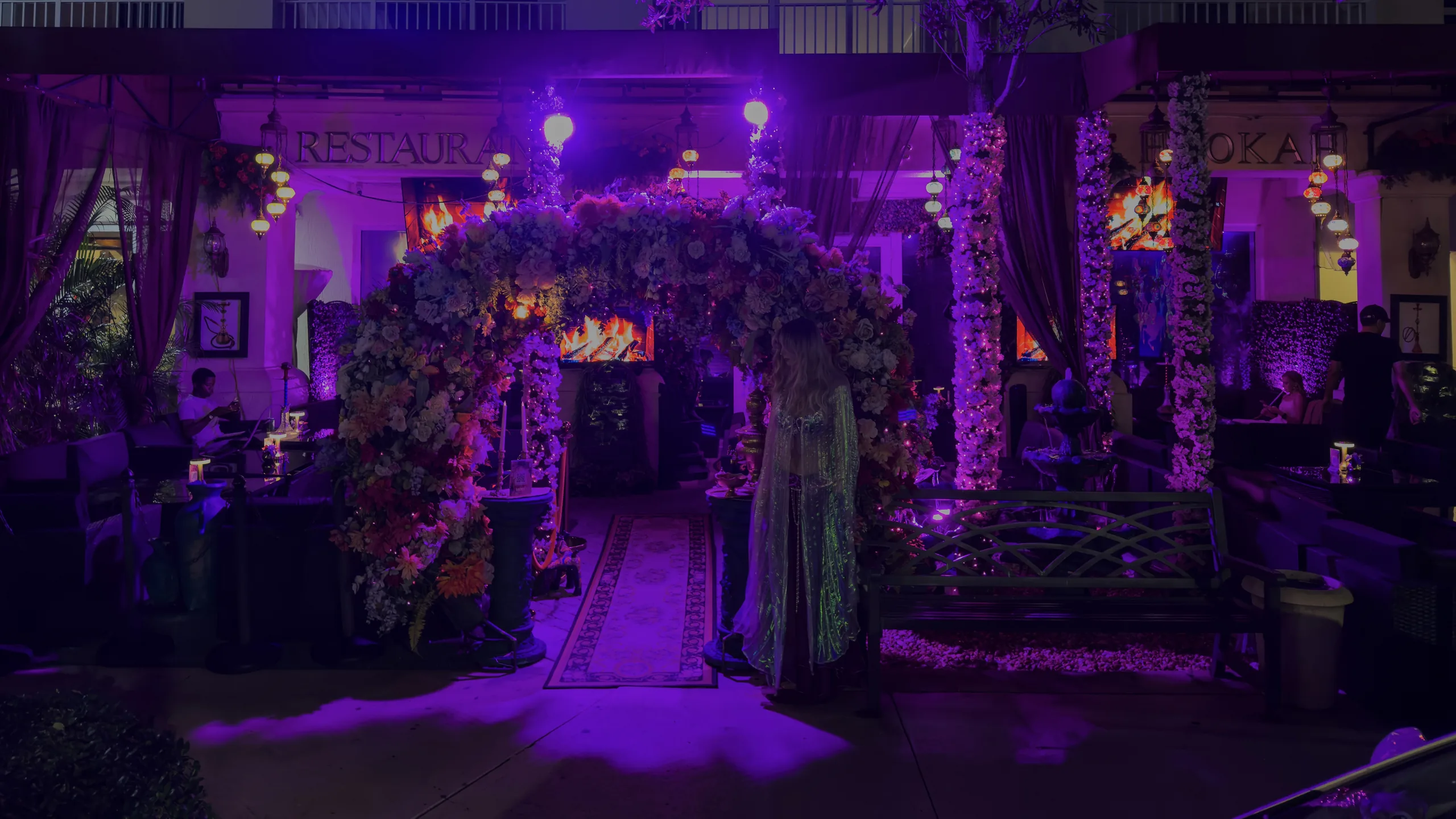 Reef Hookah & Grill courtyard at night, floral arch and lanterns